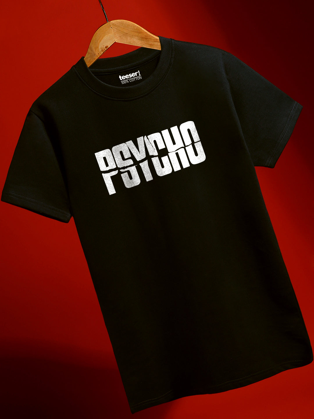 Black t-shirt with 'PSYCHO' print on a wooden hanger against a red background